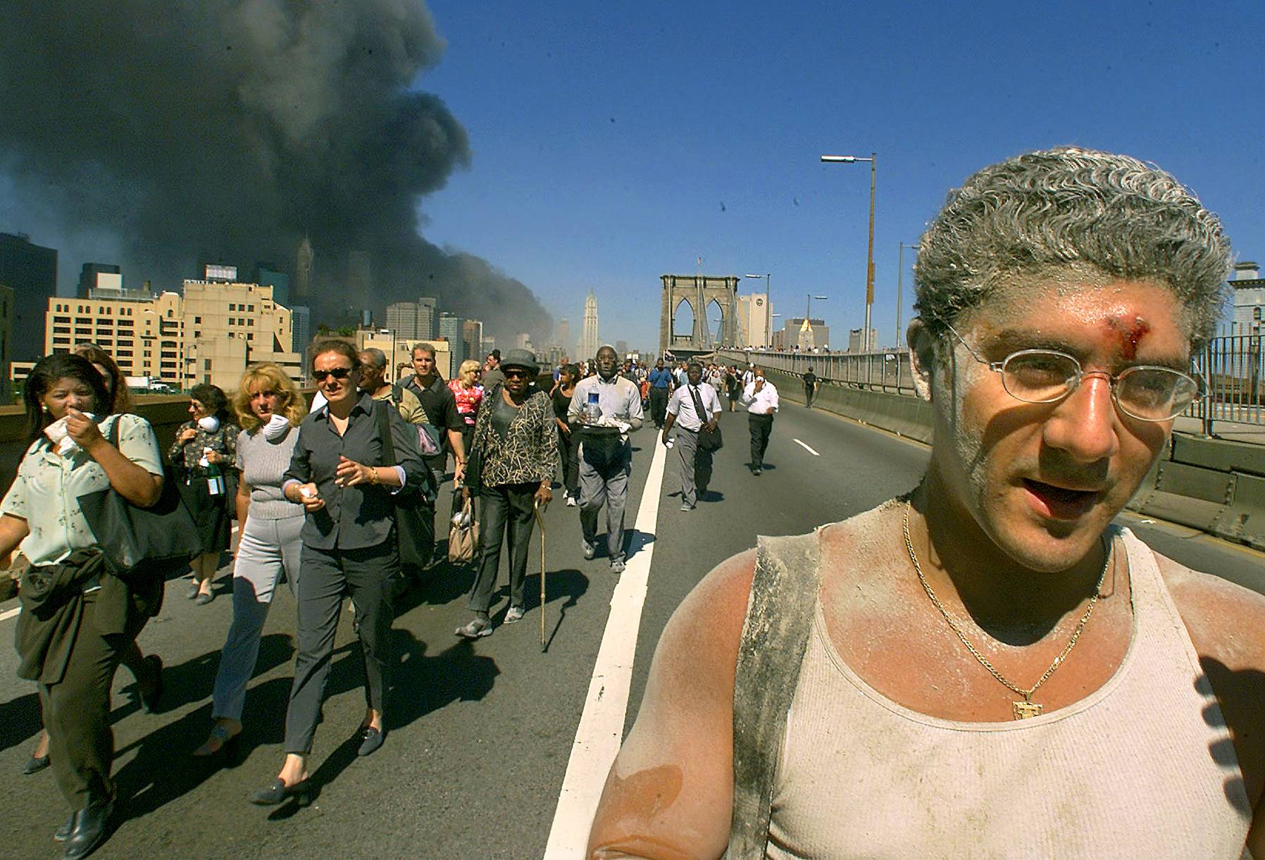 Joseph Sylvester (right) joins the exodus of people crossing the Brooklyn Bridge in New York after the collapse of the World Trade Center on Sept. 11, 2001. | ANDREA MOHIN / THE NEW YORK TIMES 