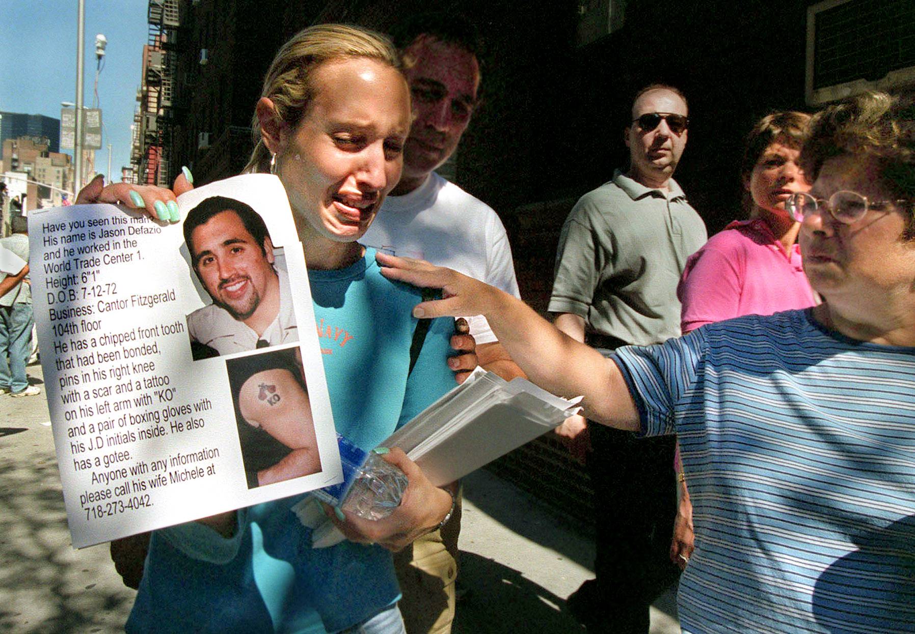 Michele Defazio is comforted by passersby as she distributes flyers bearing photos of her missing husband, Jason Defazio, in New York on Sept. 13, 2001. Jason Defazio worked as a bond trader at Cantor Fitzgerald on the 104th floor of the World Trade Center's north tower and was killed in the terror attack two days before. | KRISTA NILES / THE NEW YORK TIMES