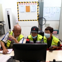 Volunteers review closed-circuit television footage in search of Chen Shaohua, who suffers from Alzheimer's, at a mall in Beijing where Chen disappeared in July.  | AFP-JIJI