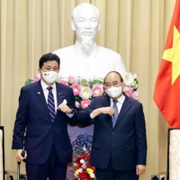 Vietnam's President Nguyen Xuan Phuc (R) bumping elbows to greet Japan's Defence Minister Nobuo Kishi during a meeting in Hanoi on Sunday. | VIETNAM NEWS AGENCY / AFP-JIJI