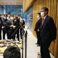 Administrative reform minister Taro Kono (right) speaks to reporters Friday in Tokyo after Prime Minister Yoshihide Suga said he would not run in the Sept. 29 Liberal Democratic Party leadership election. | KYODO