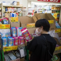 A shopper looks at a box of face masks on a shopping street in Tokyo. A recent survey showed 56.5 % of respondents in Japan believe the country needs a lockdown law | BLOOMBERG