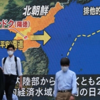 Pedestrians walk past a screen displaying a map detailing a North Korean missile launch, during a news broadcast in Tokyo's Akihabara area on Sept. 16. | AFP-JIJI