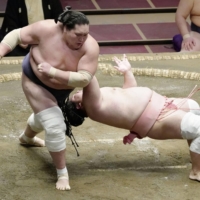 Terunofuji (left) throws down Ura during their Day 10 bout on Tuesday at Ryogoku Kokugikan. | KYODO