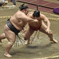 Ozeki Takakeisho (left) defeats Hoshoryu for his first win of the Autumn Basho on Wednesday at Ryogoku Kokugikan. | KYODO