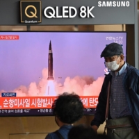 People watch a television news broadcast showing file footage of a North Korean missile test, at a railway station in Seoul on Thursday, after North Korea fired two ballistic missiles into the sea according to the South's military. | AFP-JIJI