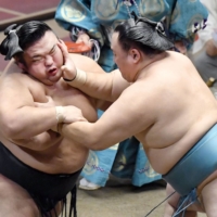 Tamawashi (right) shoves ozeki Takakeisho during their bout on Day 6 of the Autumn Grand Sumo Tournament at Ryogoku Kokugikan on Friday. | KYODO