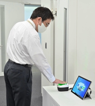 A supplied photo shows a demonstration of a system that verifies people's COVID-19 vaccination records using finger vein authentication technology. | KYODO