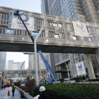 Workers remove the Tokyo Olympic emblem from the exterior wall of the Tokyo metropolitan government building on Wednesday. | KYODO