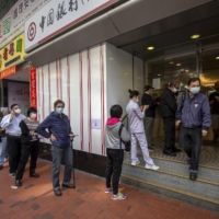 Customers queue at a Bank of China branch in Hong Kong on Tuesday. It was reported last week that two of China's biggest state-owned banks — Bank of China and ICBC — were restricting financing for purchases of Russian commodities. | BLOOMBERG