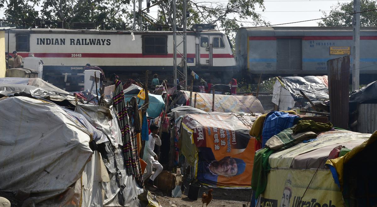 A train passes near a settlement near Haldwani railway station.