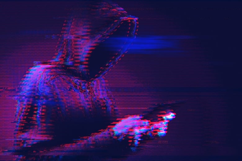 A hooded figure holds a cell phone, in an edited, over-pixelated image.