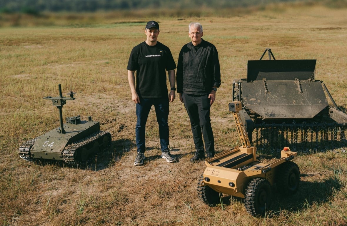 Mykhailo Fedorov and Timothy Snyder, standing alongside several ground drones.