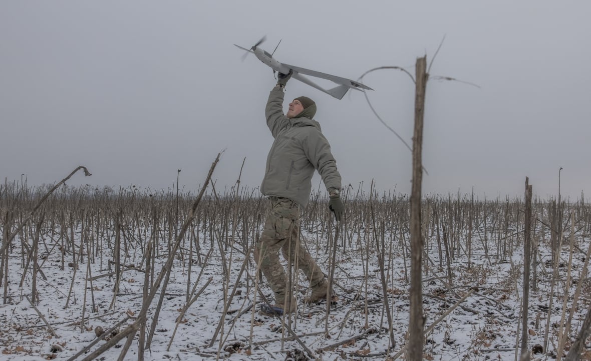 A member of a Ukrainian drone team launches a surveillance drone by hand.