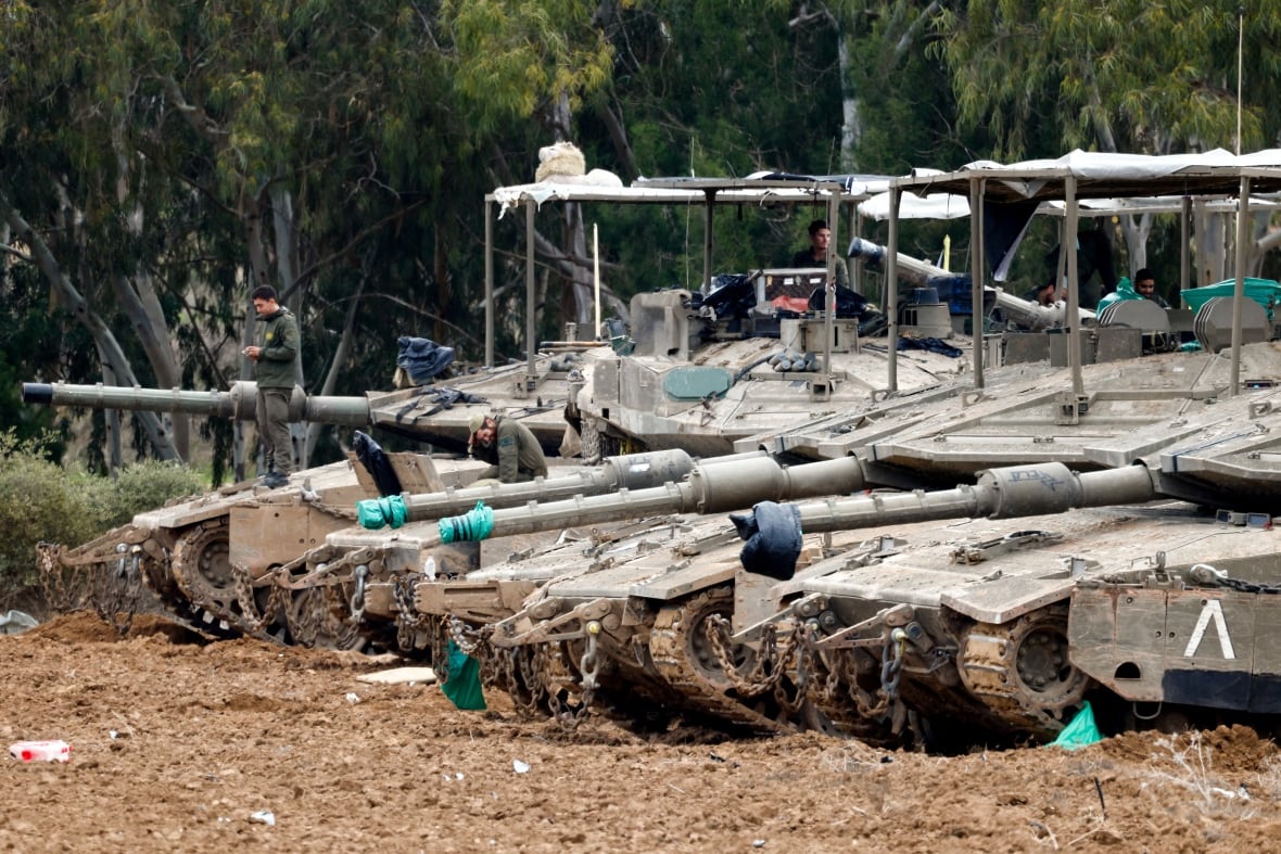 Soldiers rest on their tanks.