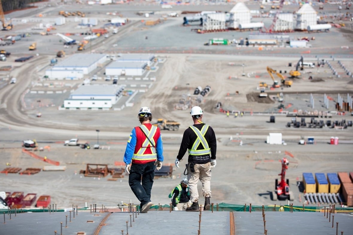 Two workers walk toward a large pit ready for construction.