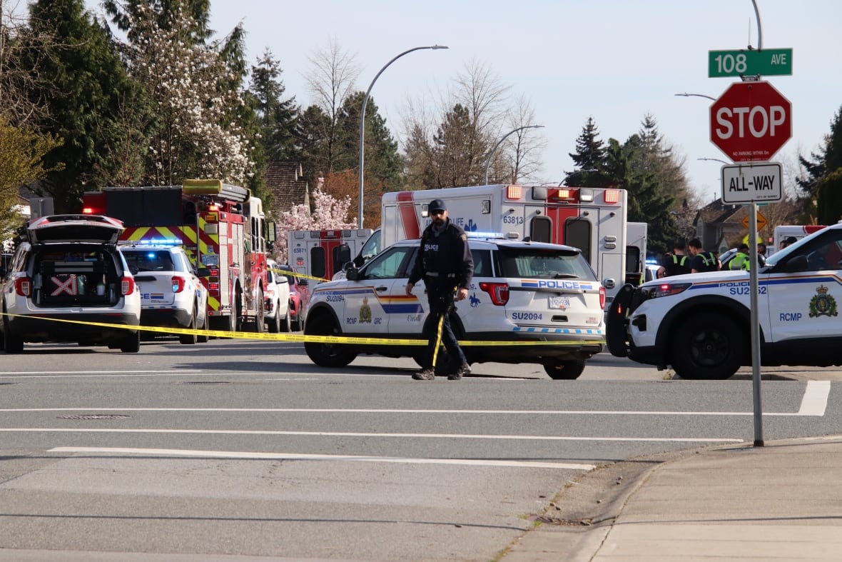 The scene of a collision taped off with ambulance and police cars in the background.