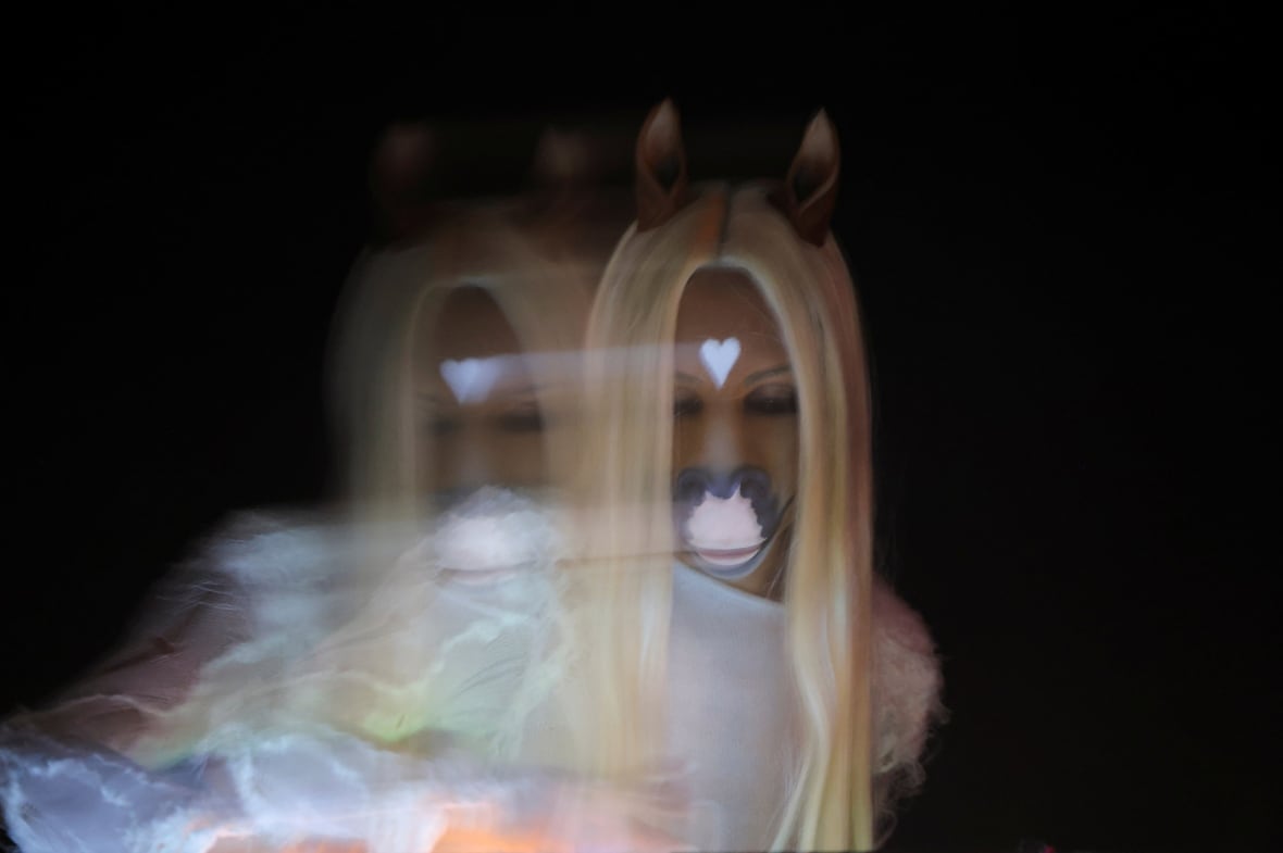 A female performer performing on stage wearing ears and nose in the shape of a horse