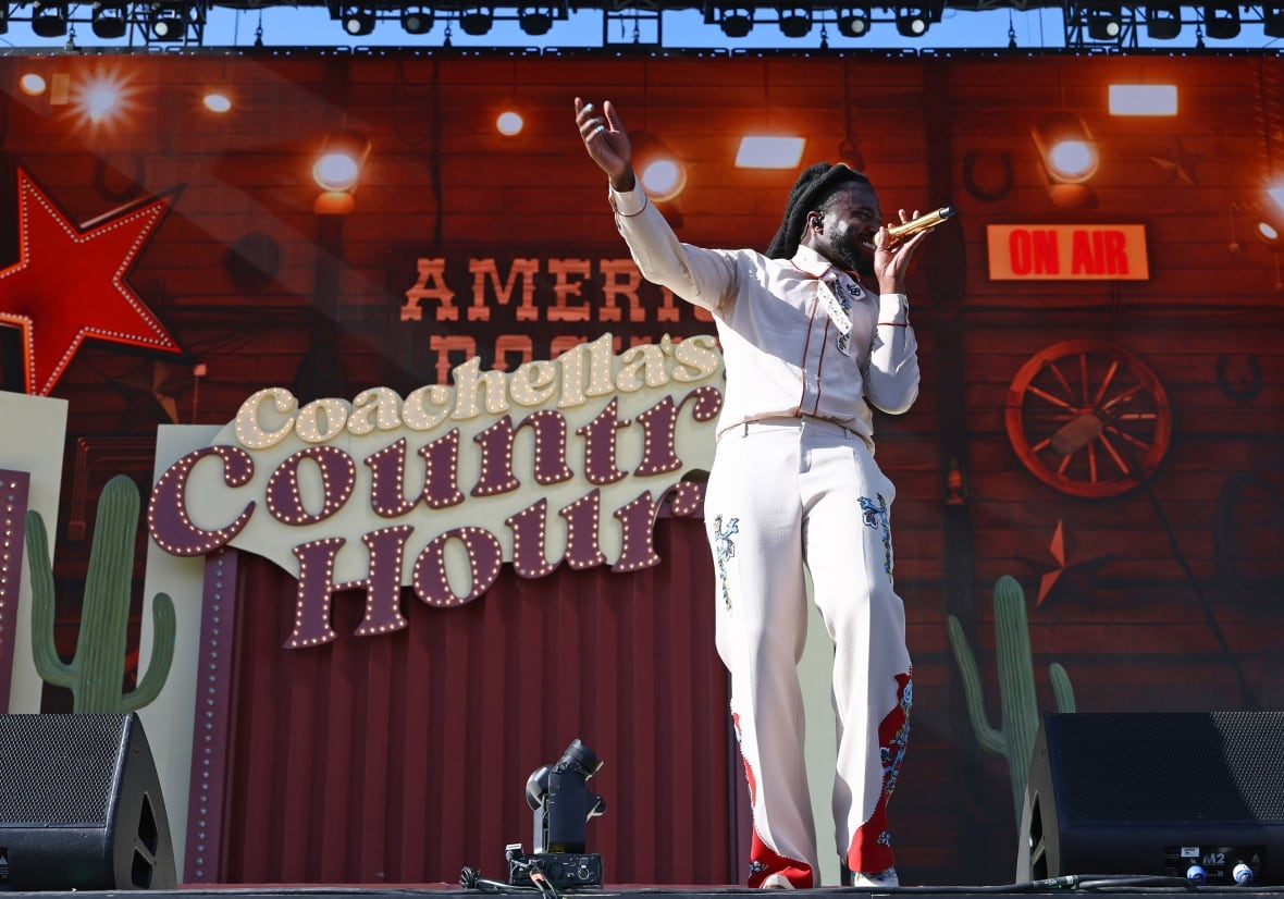 A Black country music singer performing on stage with a sign on stage that reads: Coachella's Country Hour.