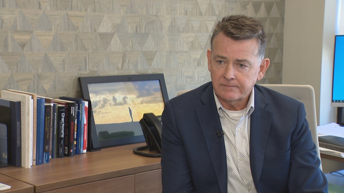 Man sits in chair at desk. 