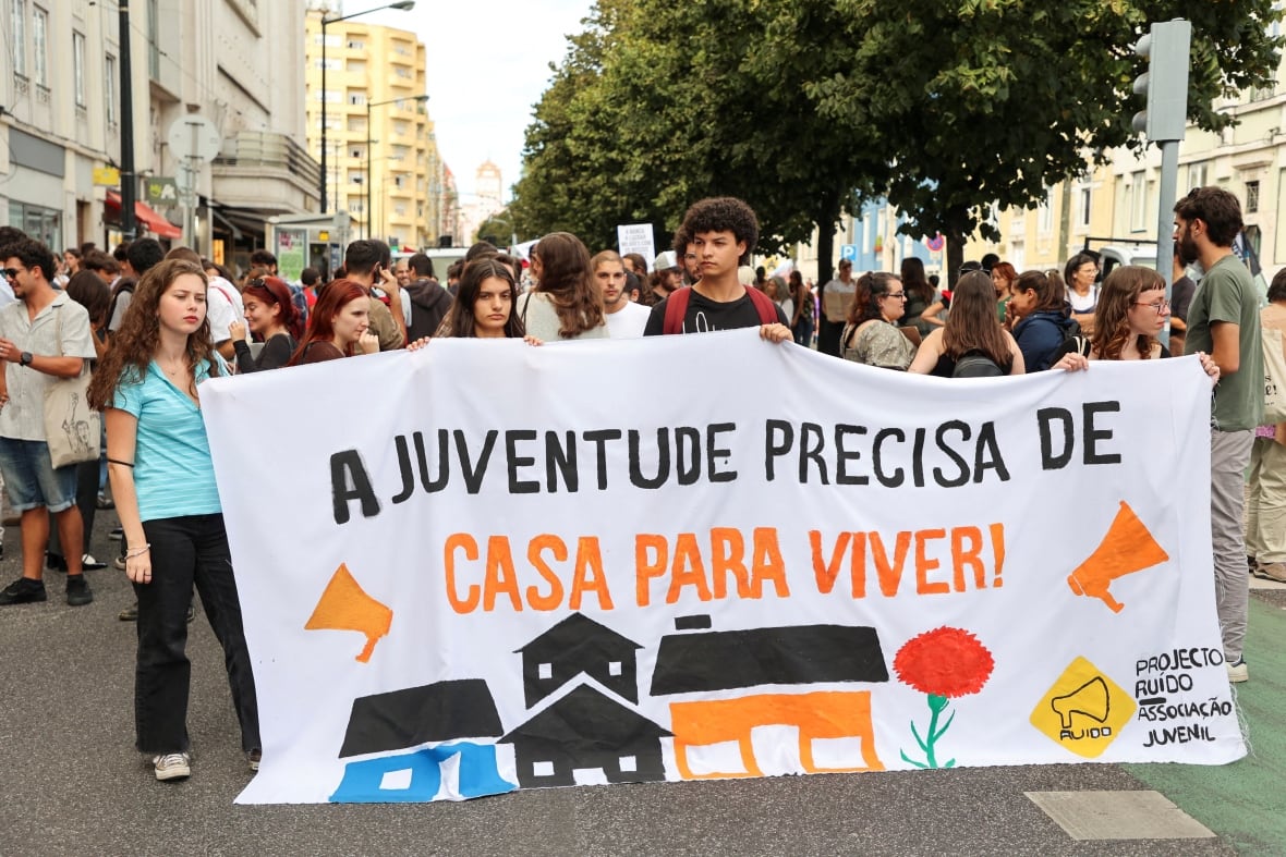 Young people walk in a street holding signs in protuguese