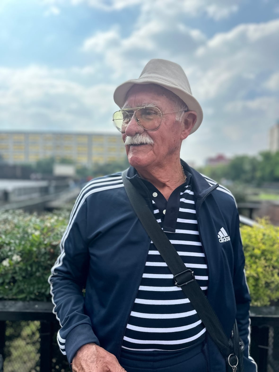 An old man in a hat and glasses looks off to the side