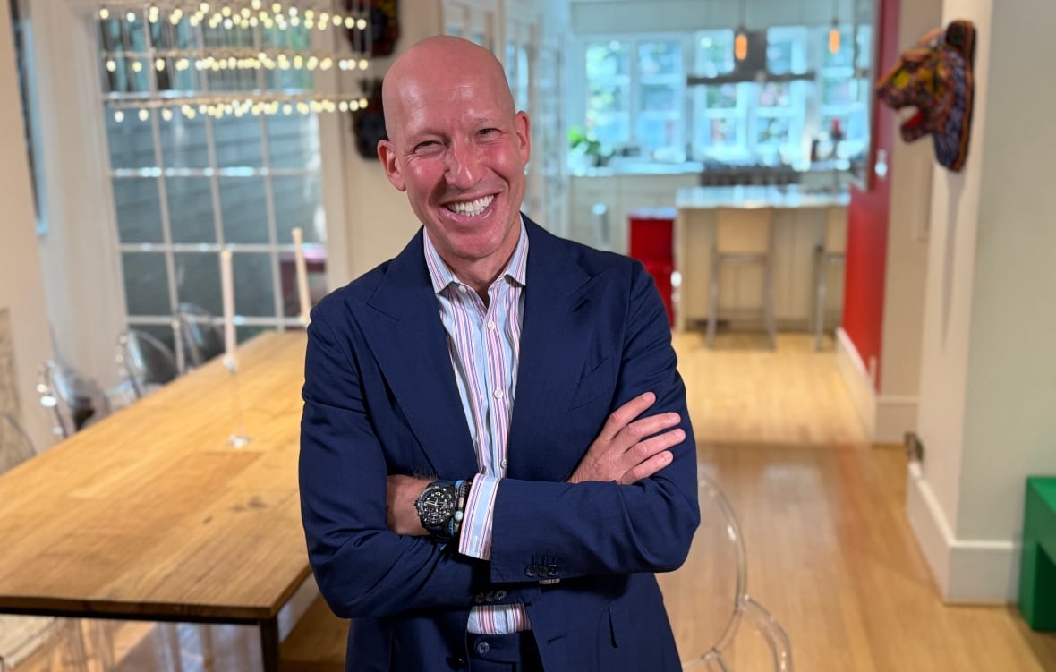 Man in a suit standing in a dining room.