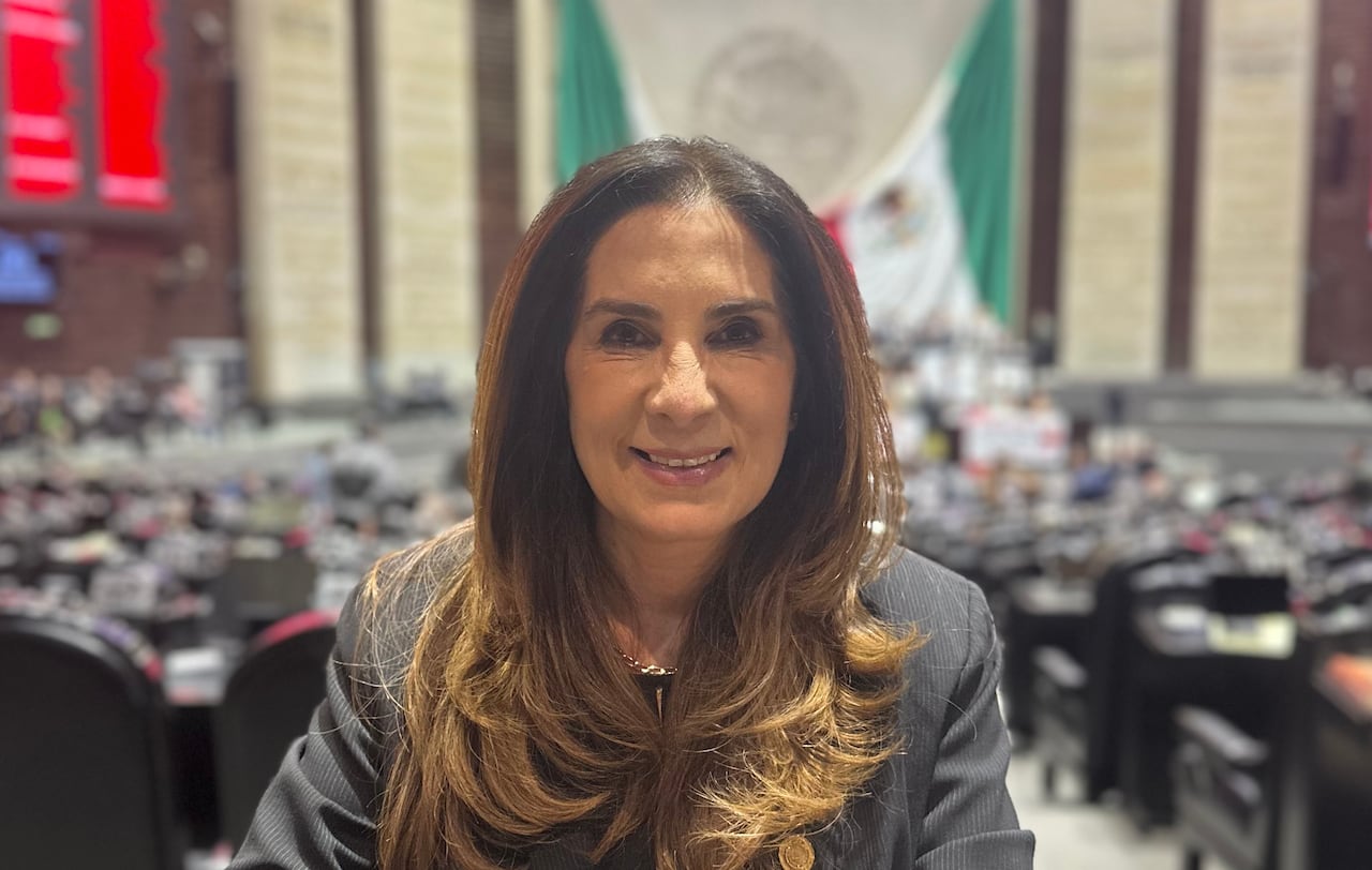A woman with combed long hair looks into the camera.