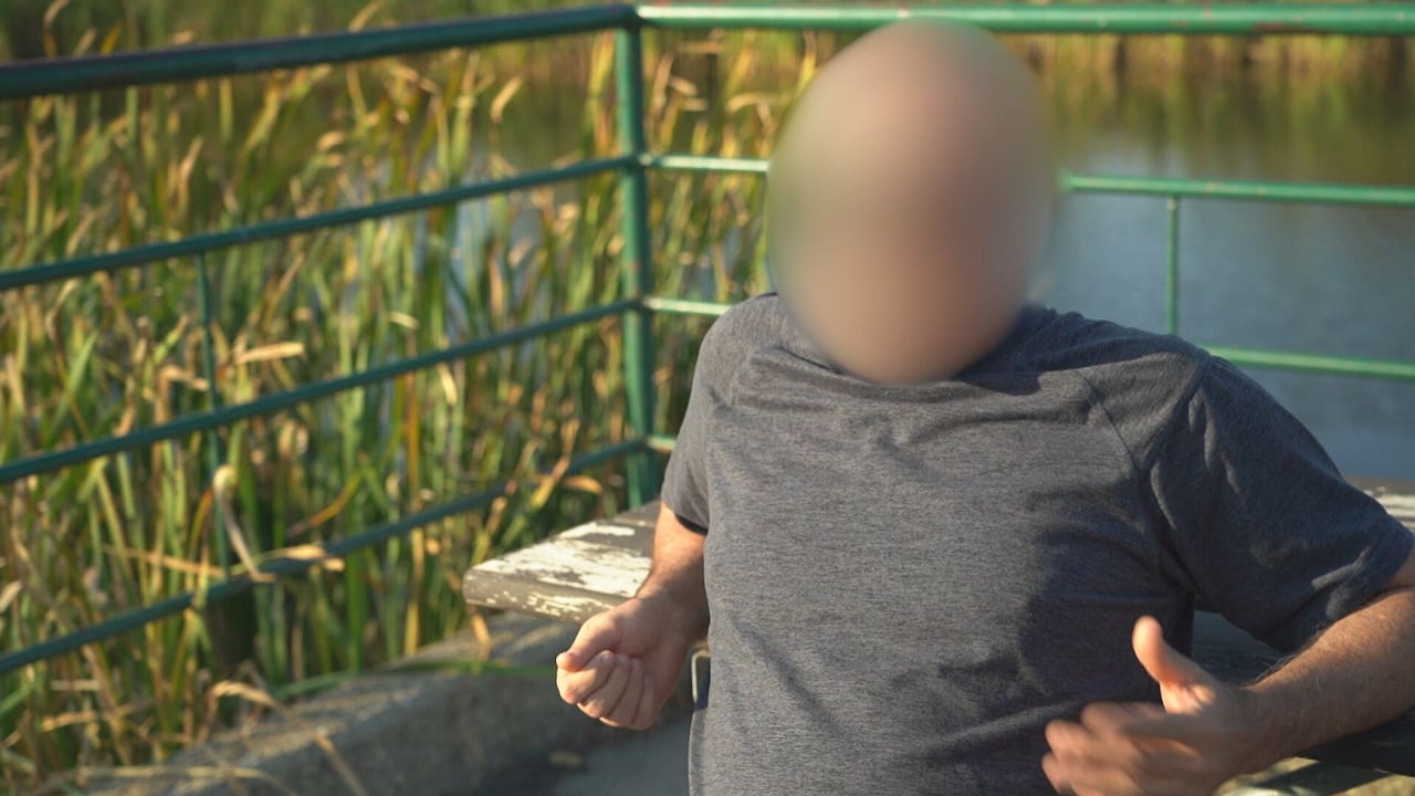 A blurred man sitting in front of a park bench.