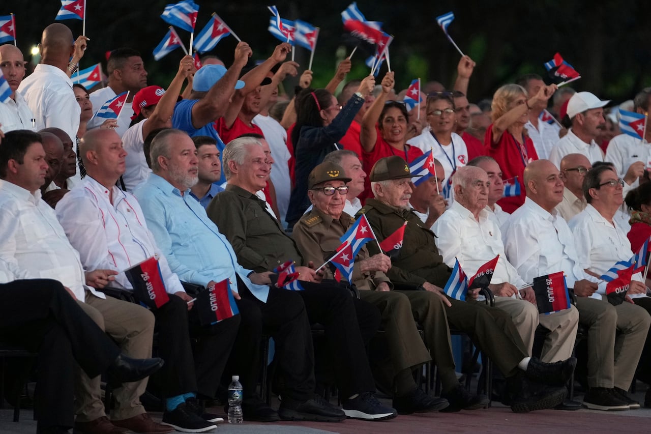 A group of people sitting and standing waving small flags.