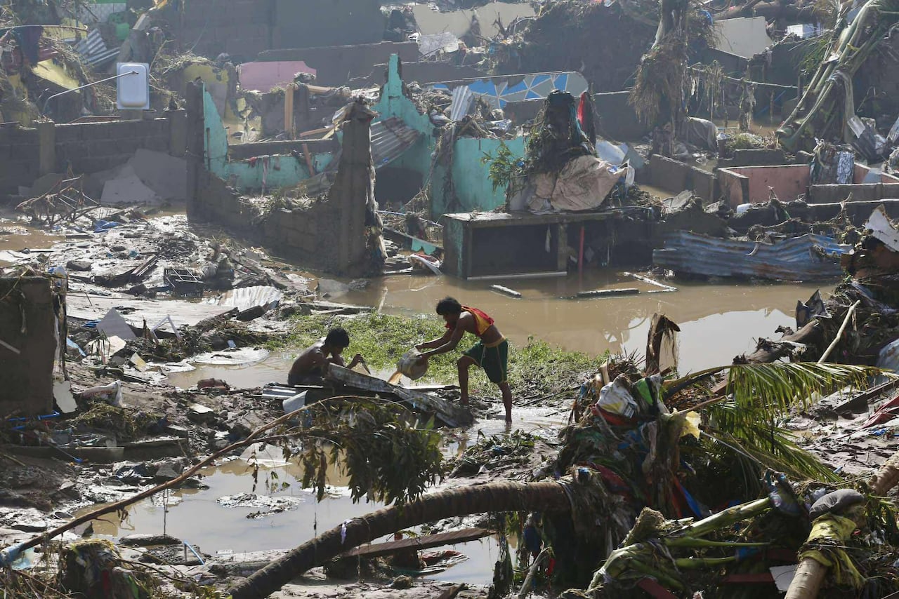 People stand in muddy rubble