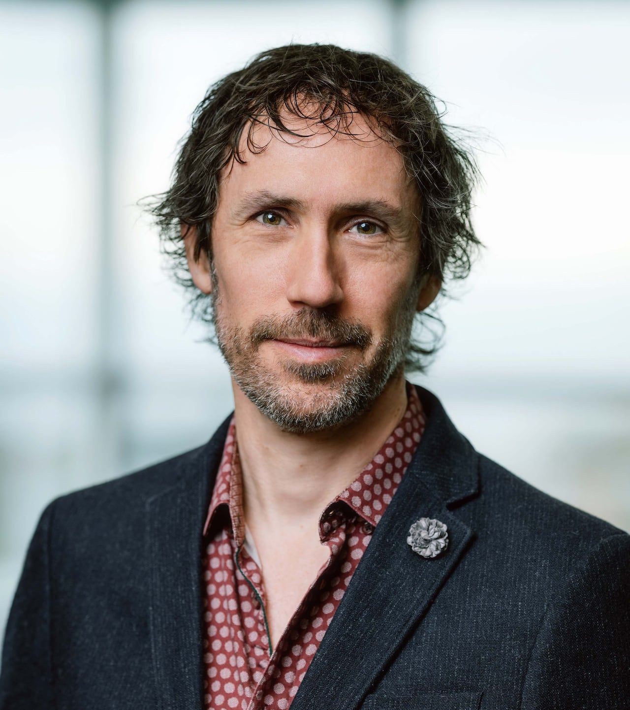 A man with a beard smiles at the camera