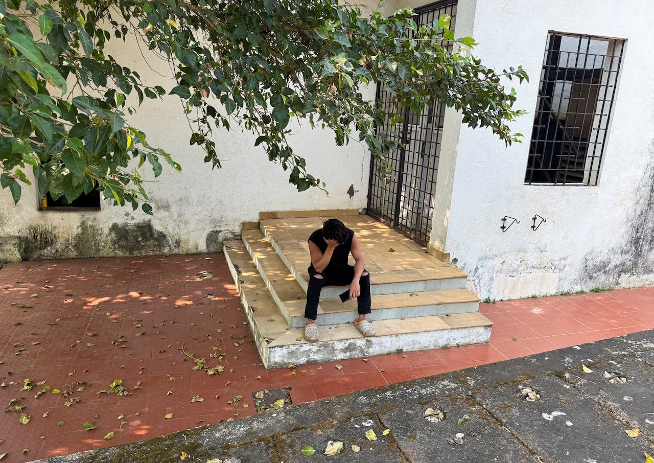 A young man dressed in black sits on some steps and leans his head on his hand.