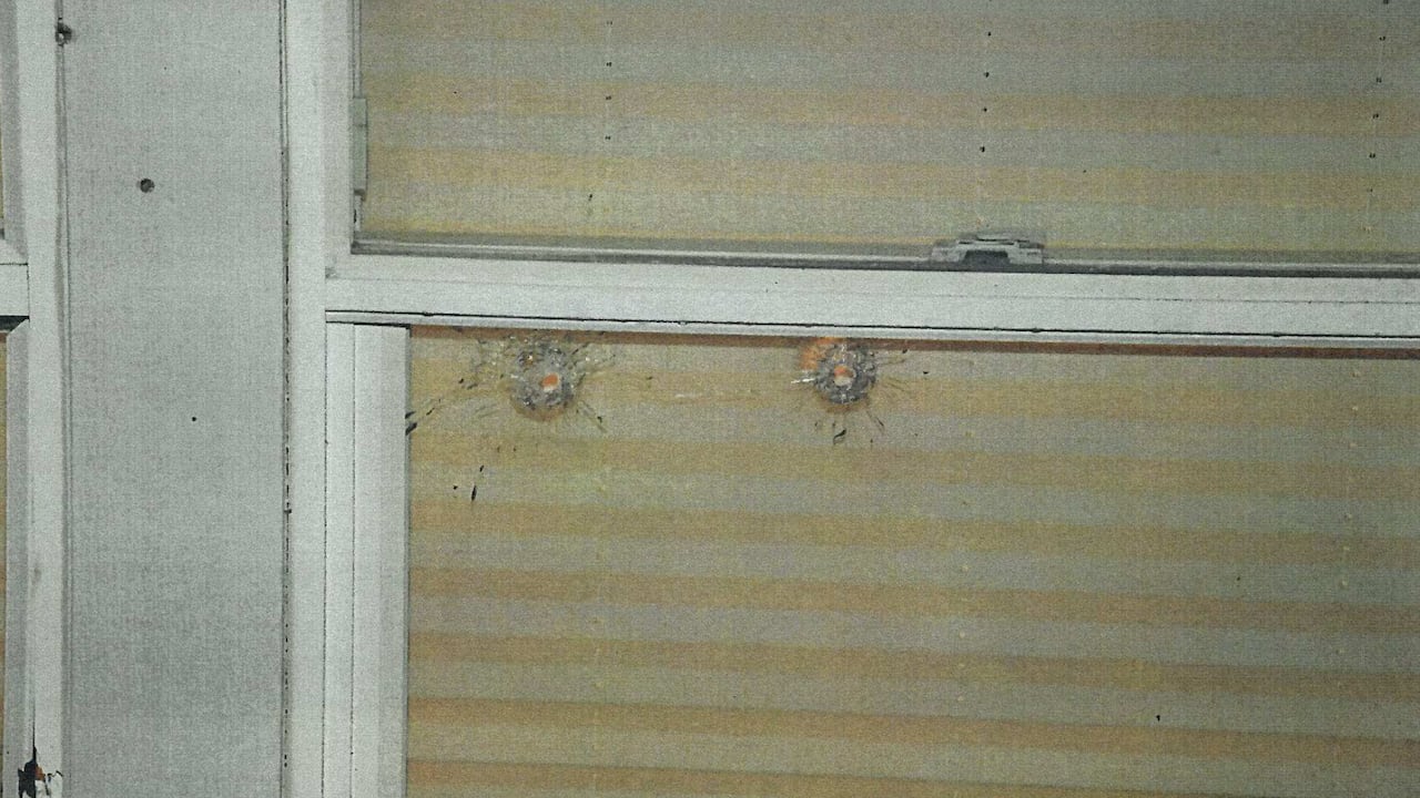 Bullet holes are seen in a window.