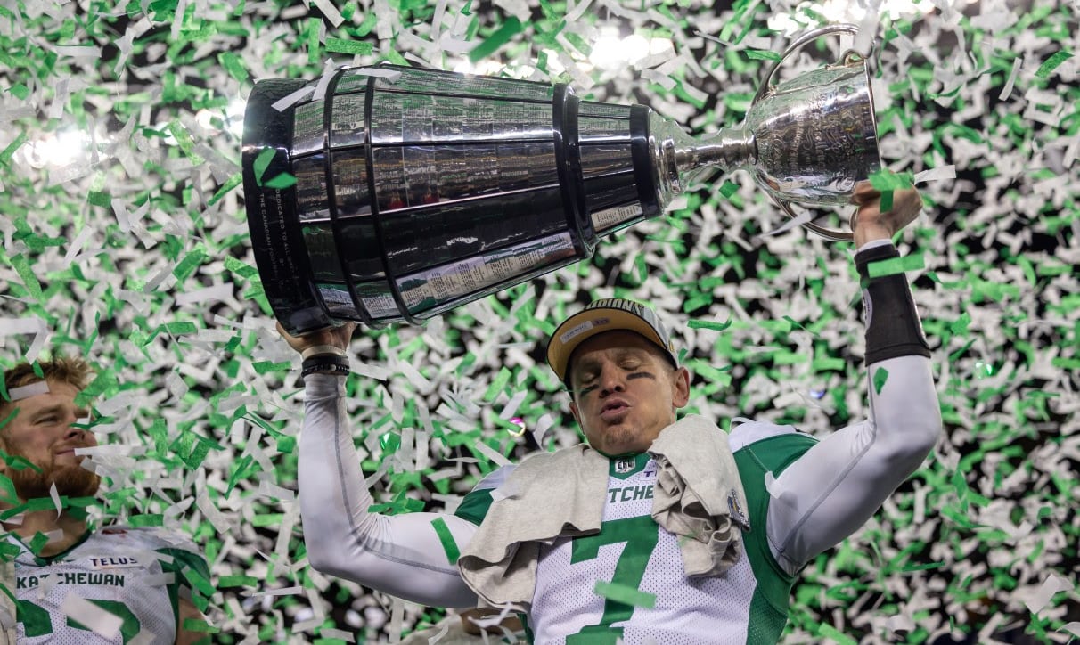 A men's football player raises a trophy above his head.