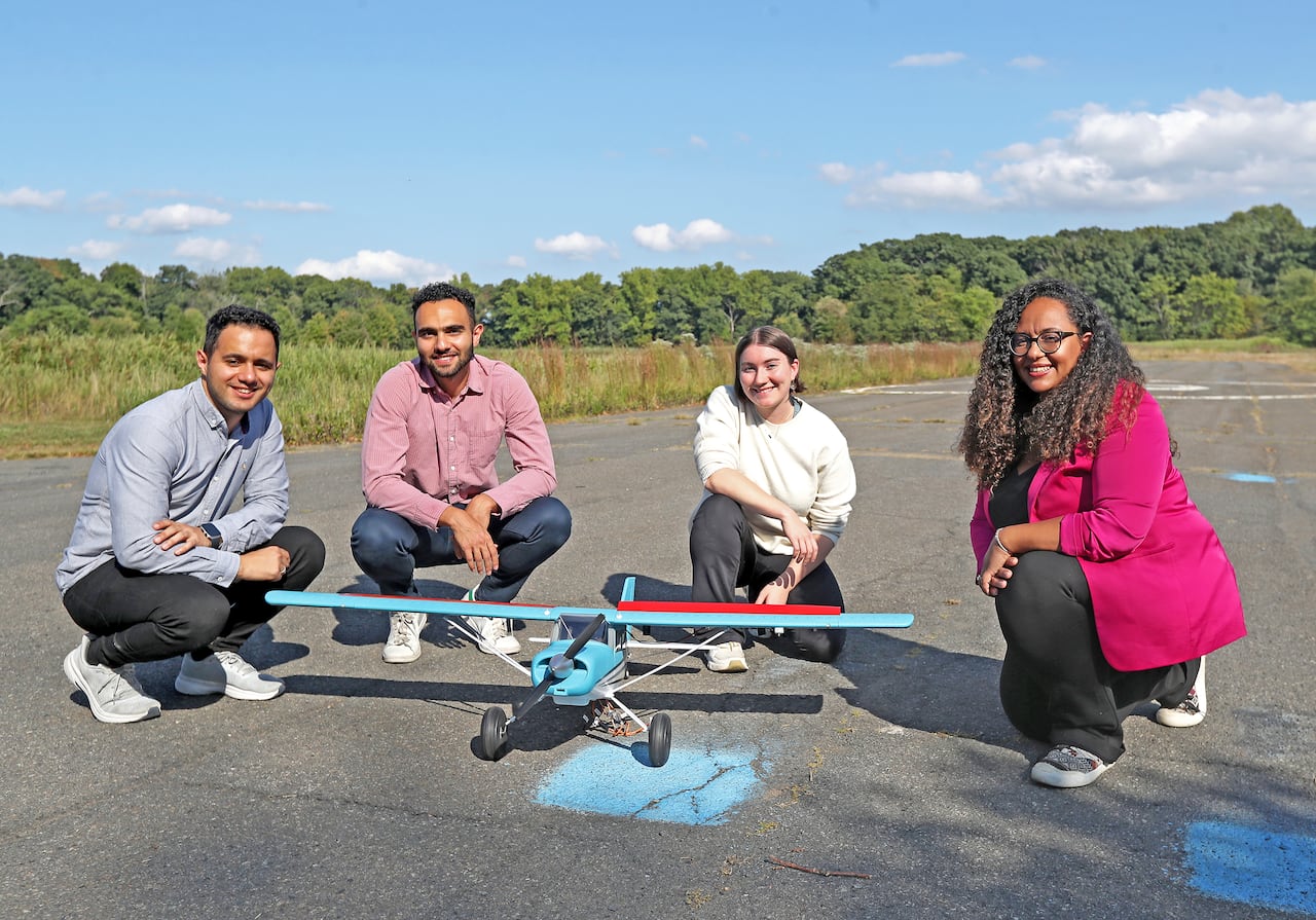 Four people surround a remote-controlled model plane.